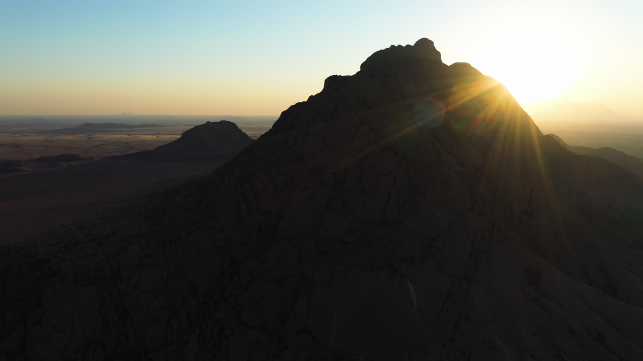 Veduta aerea intorno a una montagna rocciosa nel deserto del Namib con un raggio di sole in Namibia.