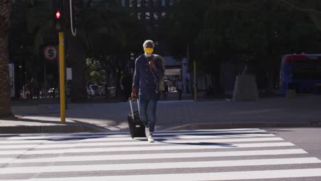 african american senior man with trolley bag crossing the road