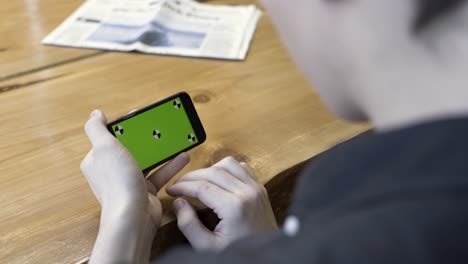 person using a smartphone with a green screen