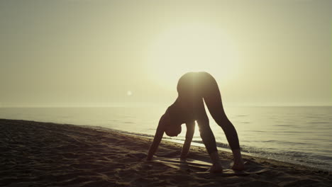 silhouette yoga woman exercising on beach. girl training flexibility at sunset.