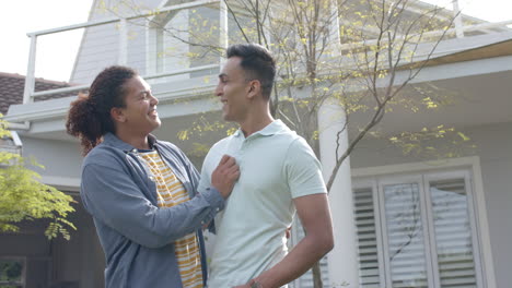 portrait of happy diverse gay male couple with new house keys embracing in garden, slow motion