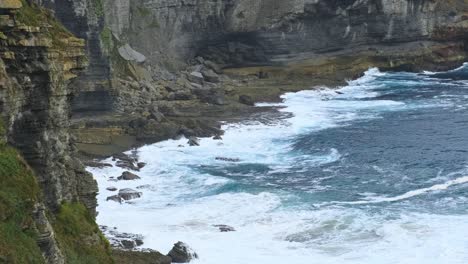 el oleaje del mar cantábrico azul golpeando el borde rocoso de la isla de isla, cantabria