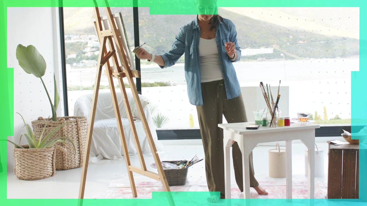 Woman artist selecting brush as green graphics recede, painting landscape by window for education