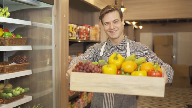 Commesso di supermercato cordiale che espone prodotti freschi