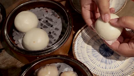 hands preparing steamed buns on a plate