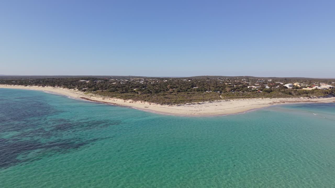 Droneoptagelse af en sandstrandtange med et roligt hav og lavt vand.