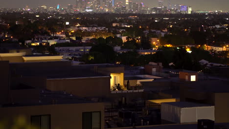person on their apartment balcony in front of downtown los angles illuminating light pollution as air planes slowly fly overhead.