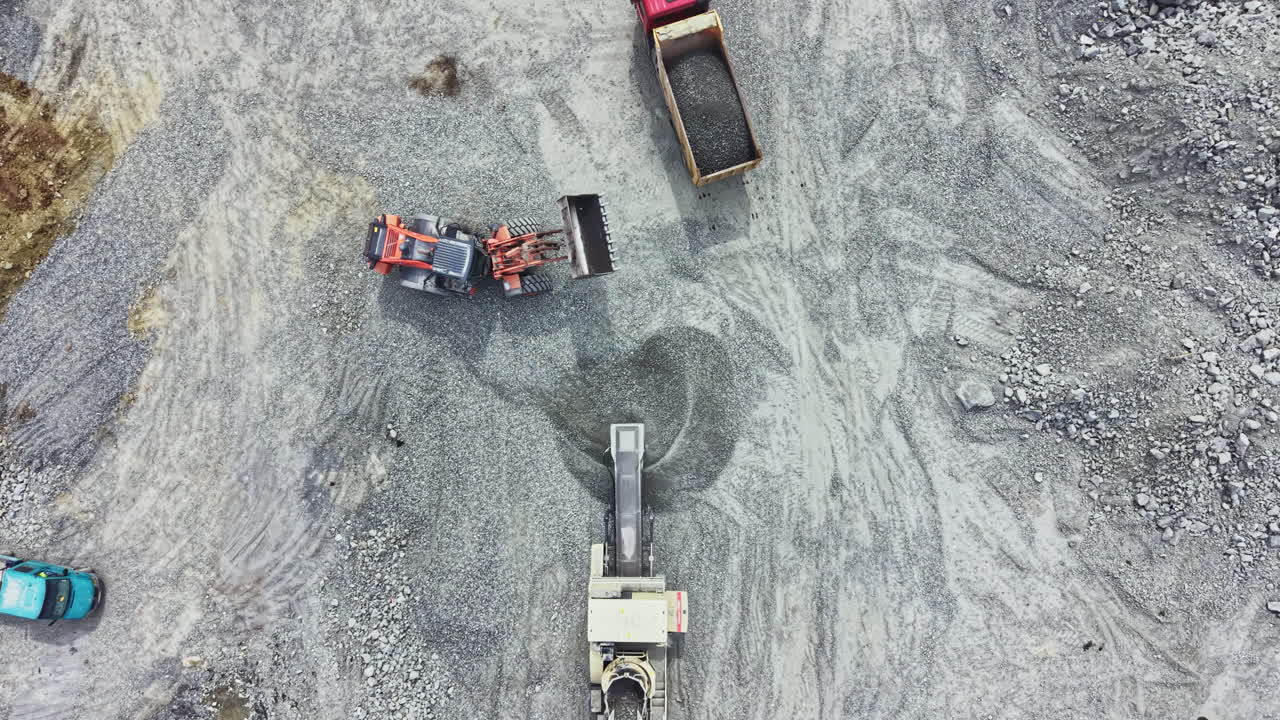 Granite quarry operation showing heavy machinery and trucks during a busy workday in the mining industry