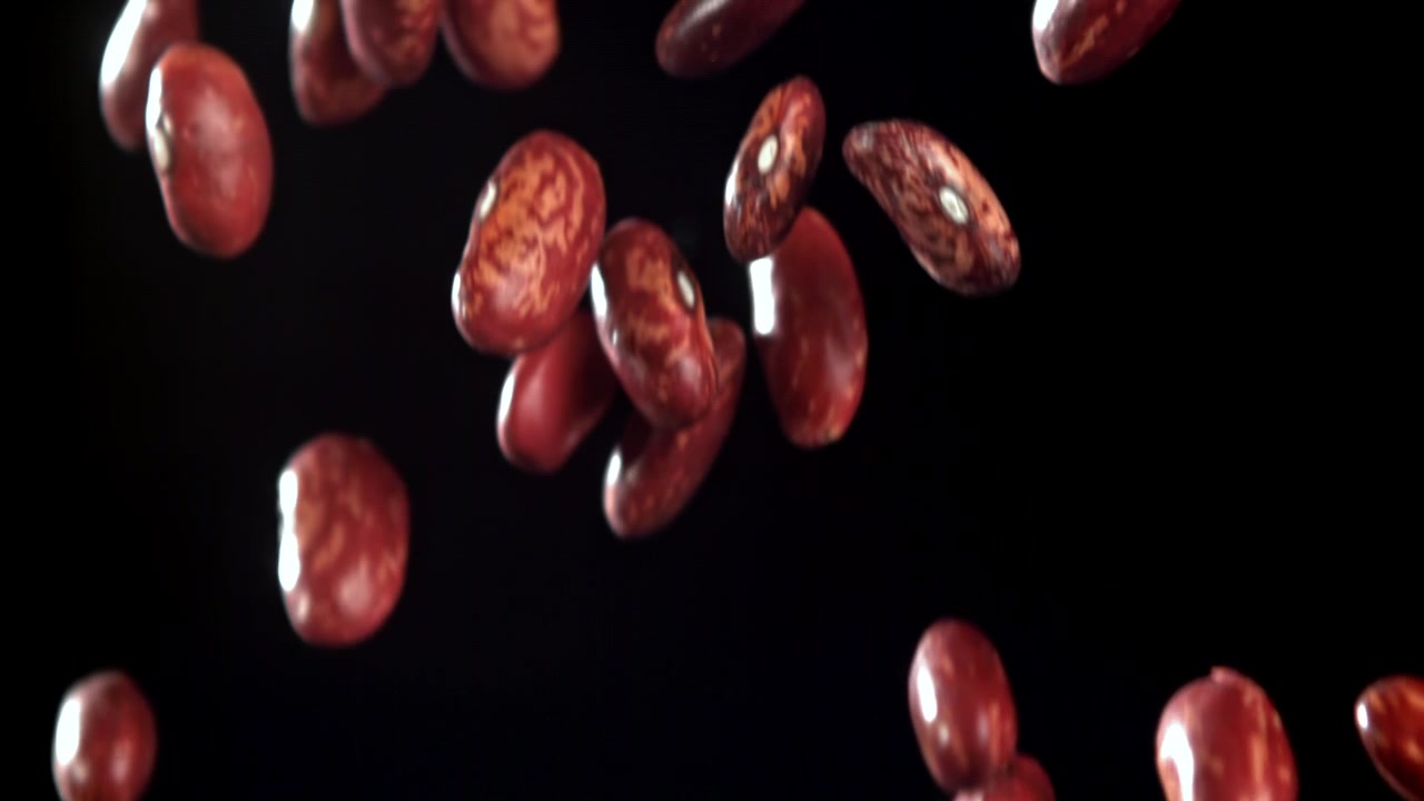 Red Kidney Beans Falling in Slow Motion Against a Black Background