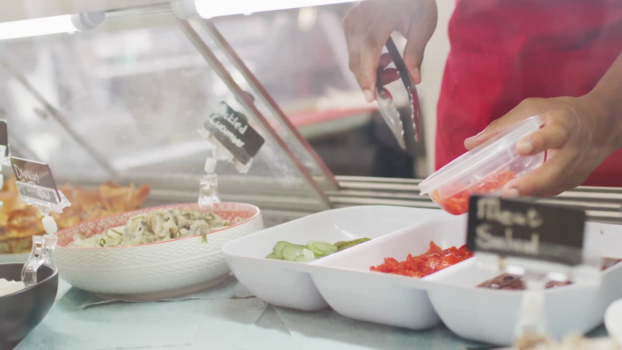 video de las manos de una mujer biracial poniendo comida en una caja