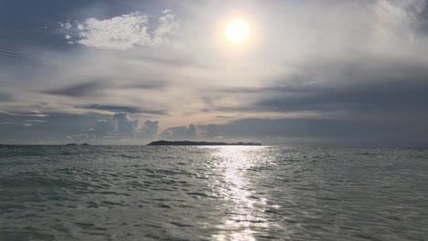 Drone-flying-low-over-the-waves-in-the-ocean,-in-direct-sunlight-on-a-sunny-day