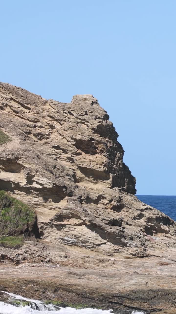 las olas golpean las rocas en una costa soleada