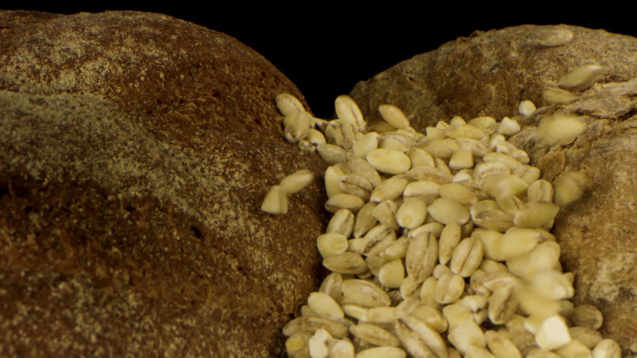 pan delicioso fresco aislado sobre fondo negro. imágenes de stock. primer plano de pan de centeno rústico con corteza crujiente y semillas que caen, concepto de nutrición saludable