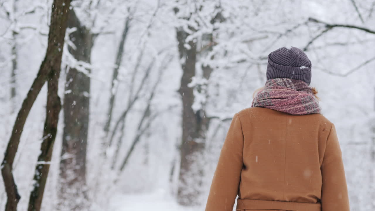 세련된 여성이 눈 덮인 공원을 산책합니다.