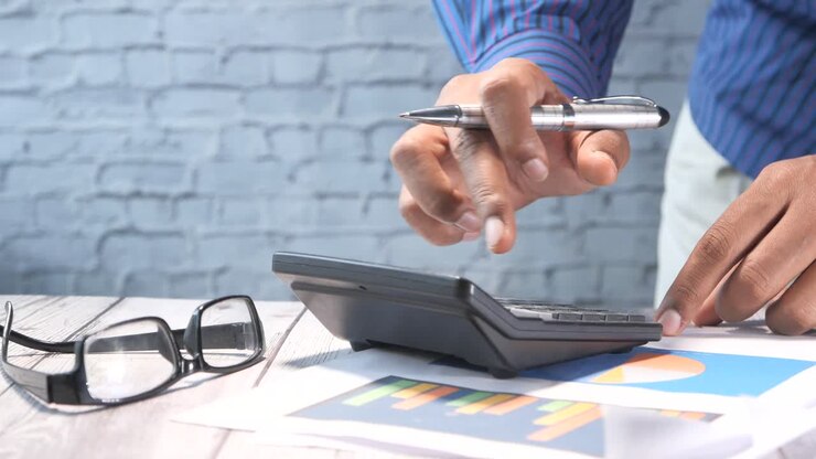Businessman Using Calculator and Charts
