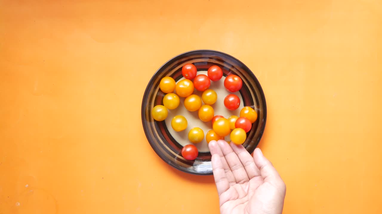 Hand picking cherry tomatoes from a plate