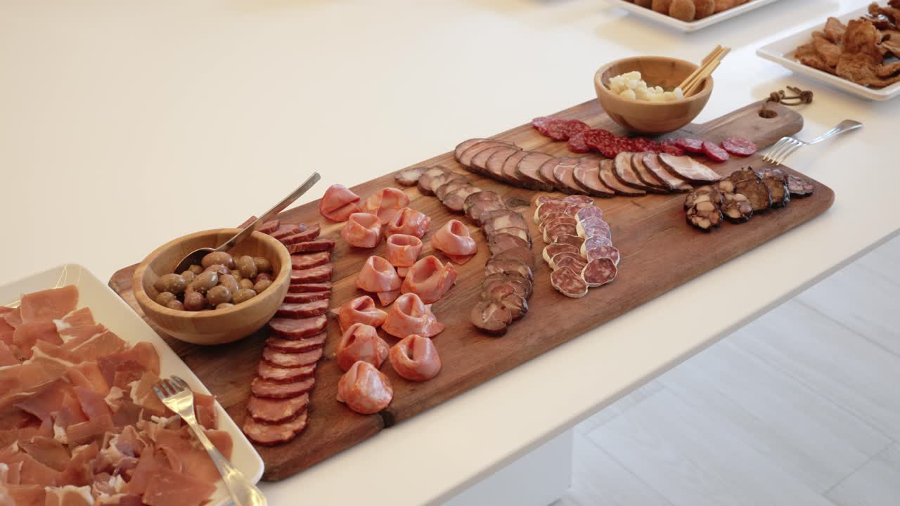 Charcuterie board with cured meats olives and sides served on white table