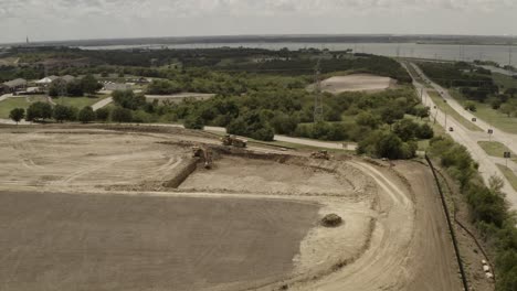 Un-Camión-Volquete-Viaja-En-El-Sitio-De-Construcción-Dentro-De-Una-Ciudad-Al-Lado-Del-Lago