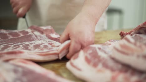 Männliche-Hände-Des-Metzgers-Schneiden-Frisches-Rohes-Schweinefleisch-Auf-Dem-Tisch-Mit-Einem-Küchenmesser