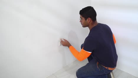 man cleaning dry painted wall with piece of cloth