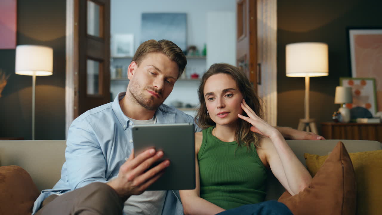 cónyuges infelices saludando tableta llamada en casa hacer zoom en. mujer triste agitando almohadilla de mano