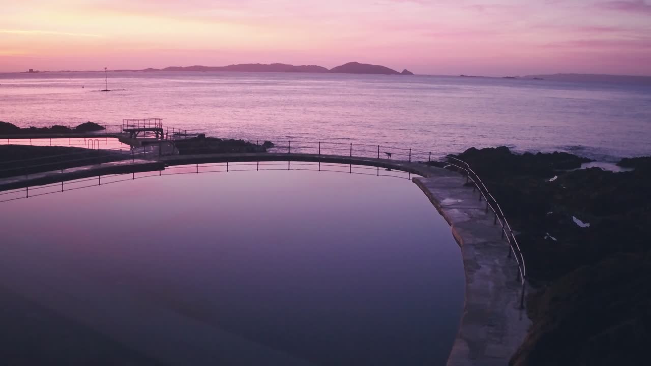 Guernsey tidal bathing pools with Herm Island behind at sunrise, Channel Islands, UK. Aerial drone view