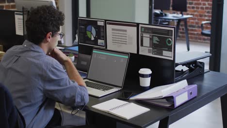 hombre caucásico sentado en el escritorio codificando datos en una computadora portátil