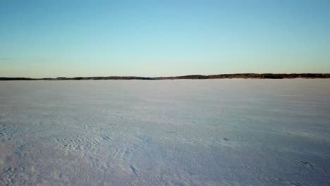 Aerial-Drone-Footage-Of-Snow-And-Ice-On-A-Frozen-Body-Of-Water-On-A-Cold-Winter-Day-In-Rural-Midwest,-Iowa