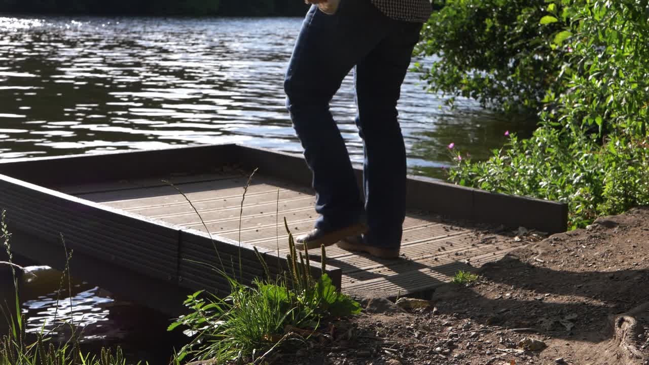 Woman in solitude walks across pier by lake medium shot