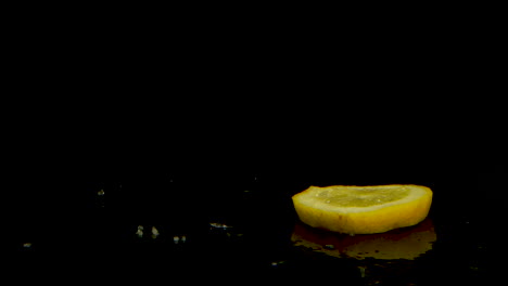 Slice-of-lemon-that-Spinning-and-falls-on-a-black-mirrored-surface