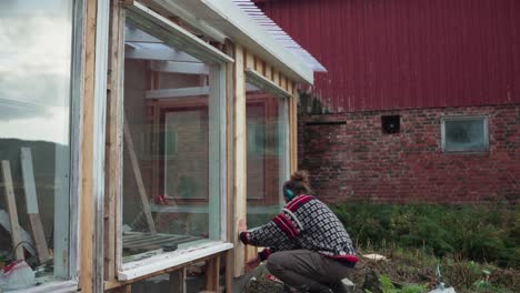 a man is constructing the frame for the glass window of the greenhouse