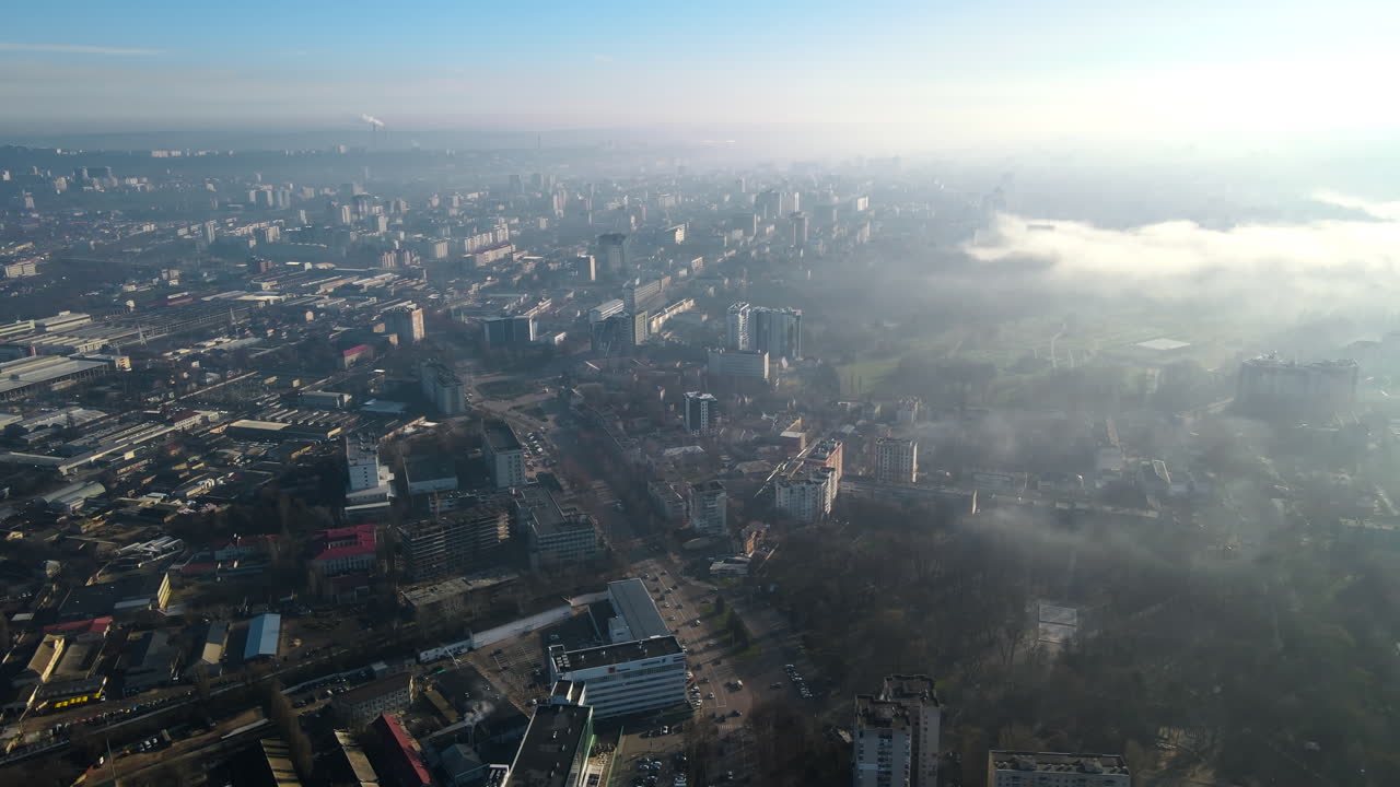 Aerial drone view of Chisinau. Panorama view of multiple buildings, roads with moving cars and bare trees. Good weather with fog in the air and low clouds. Moldova