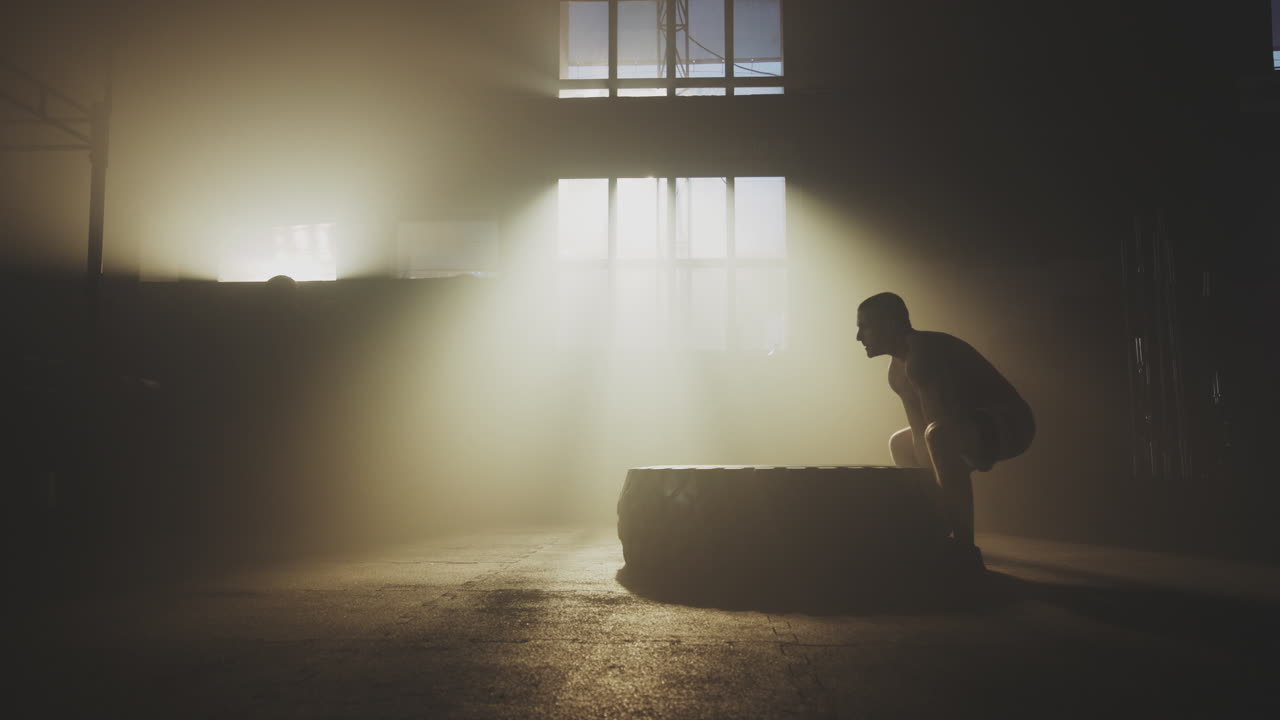 Man lifting tire in a gym