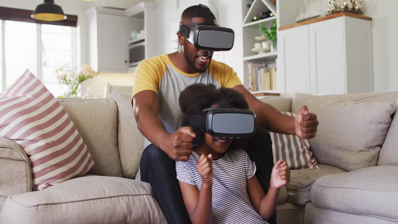 hija afroamericana y su padre jugando usando auriculares vr