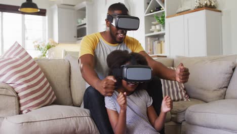 african american daughter and her father playing game wearing vr headsets