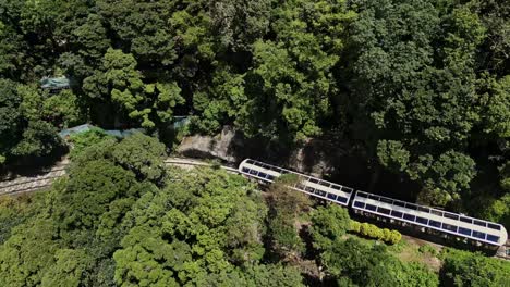 Aerial-following-the-Peak-Tram-as-it-makes-its-down-from-Victoria-Peak,-Hong-Kong