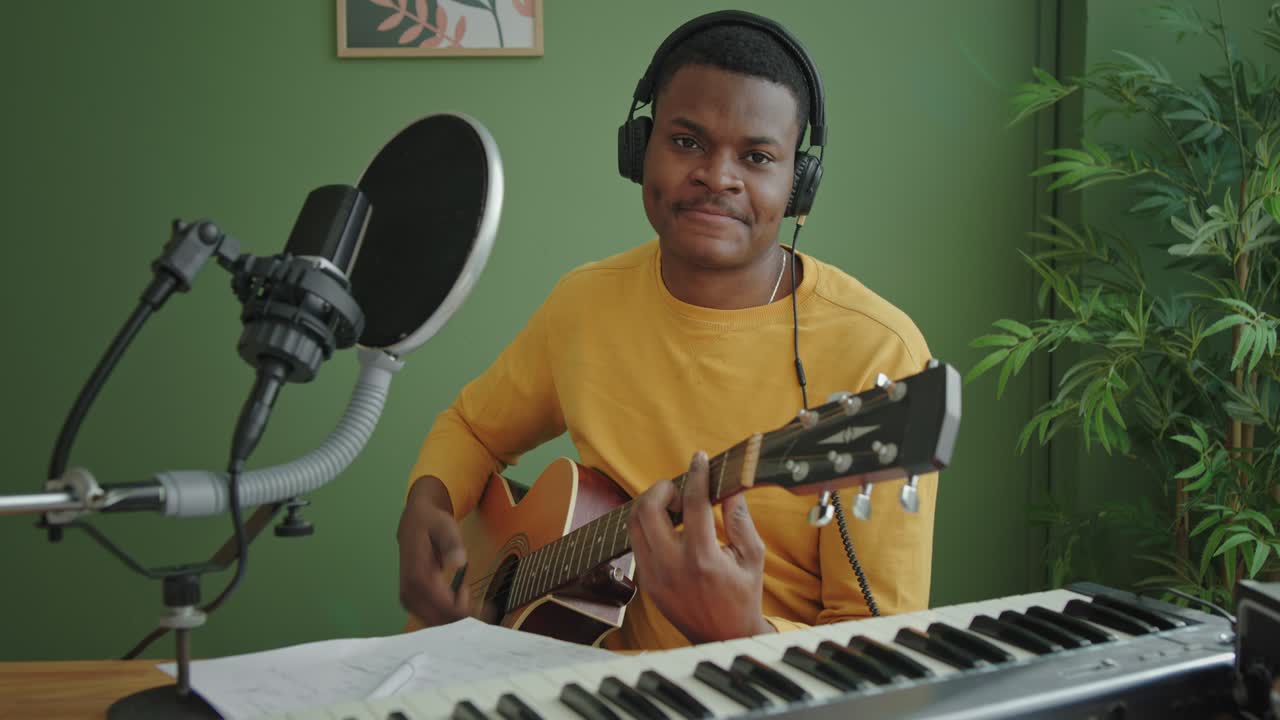 Black musician playing guitar at home
