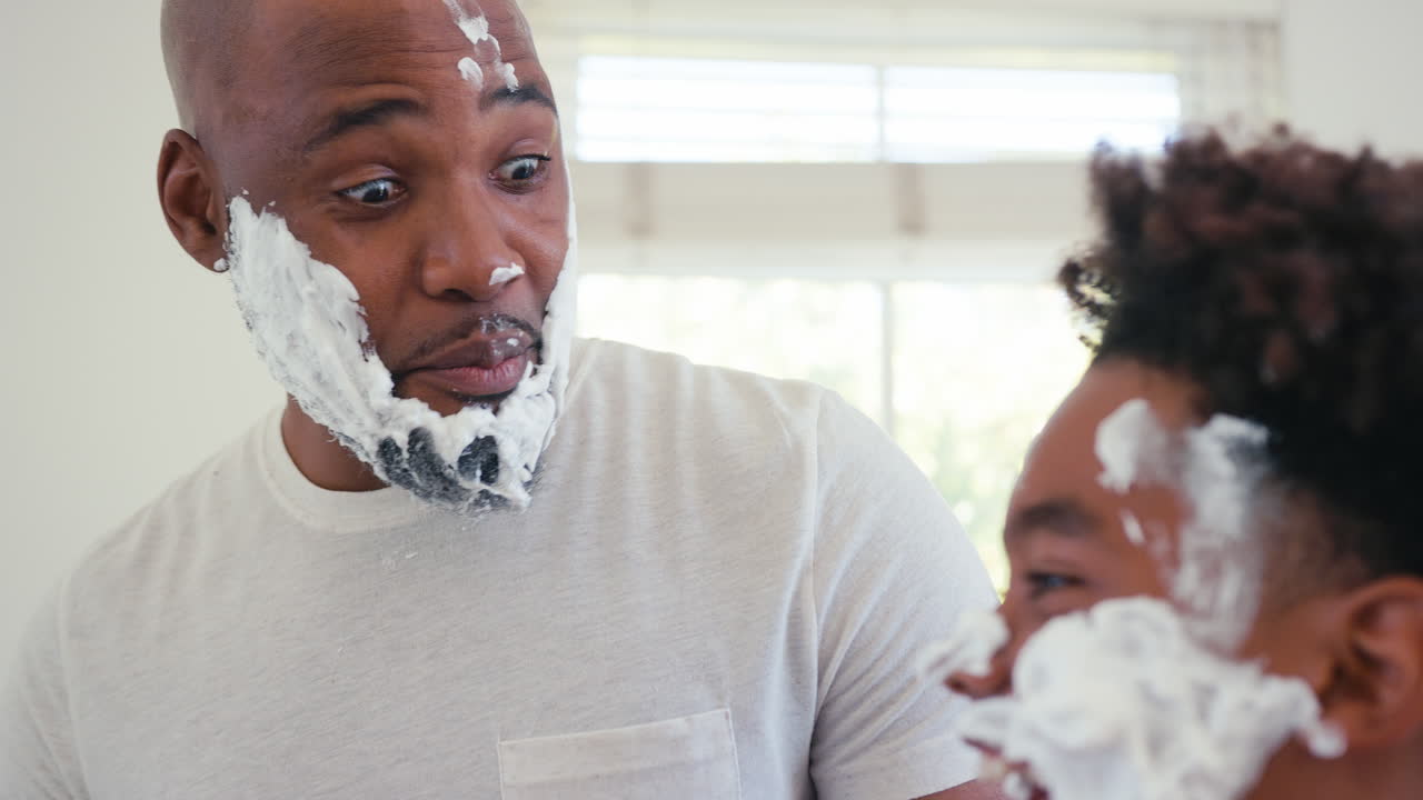 close up de padre e hijo en casa divirtiéndose jugando con espuma de afeitar en el baño haciendo un lío