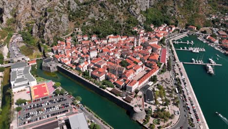 flying around the city walls fortress and kampana tower with the old town inside revealing the sea gate and port of kotor in montenegro in the summer