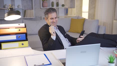 Delightful-and-cheerful-mature-businessman-using-phone,-looking-at-phone.