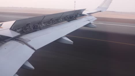 view out of an airplanes right side window while landing on abu dhabi international airport with the flaps down and spoilers and speedbrakes deployed