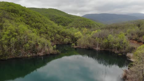 drone video low flight over lake at mountain forest sunny overcast