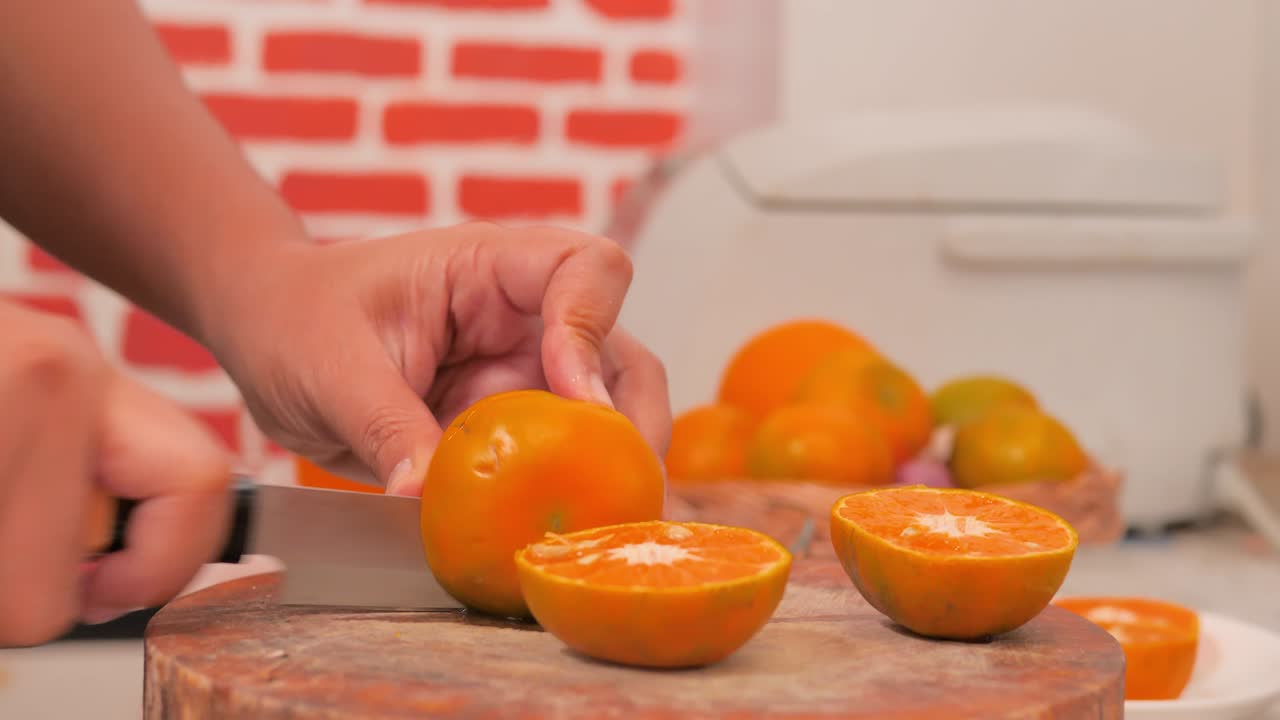 recoger naranjas y cortar por la mitad en la tabla de cortar en la cocina.