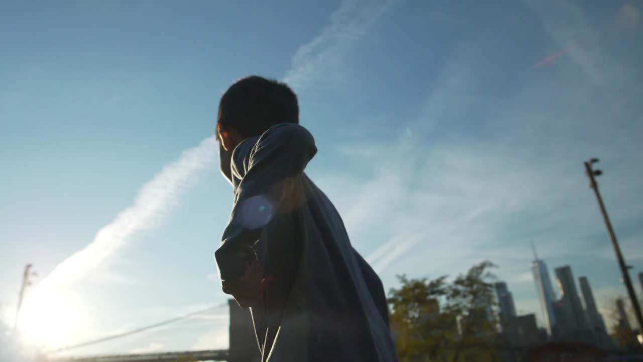 120fps 슬로우 모션으로 브루클린 다리 공원에서 저녁 햇살을 향해 행복하게 달리는 소년