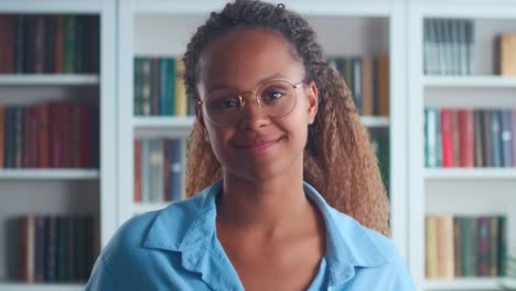 una joven afroamericana con gafas mira la pantalla y se ríe lindamente.