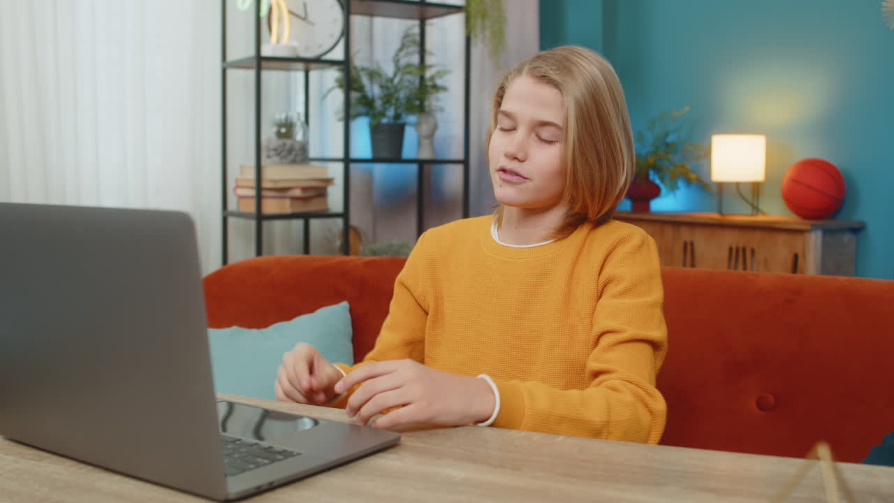 Teenager boy conducting video conference on laptop waving hand and greeting friend on couch at home