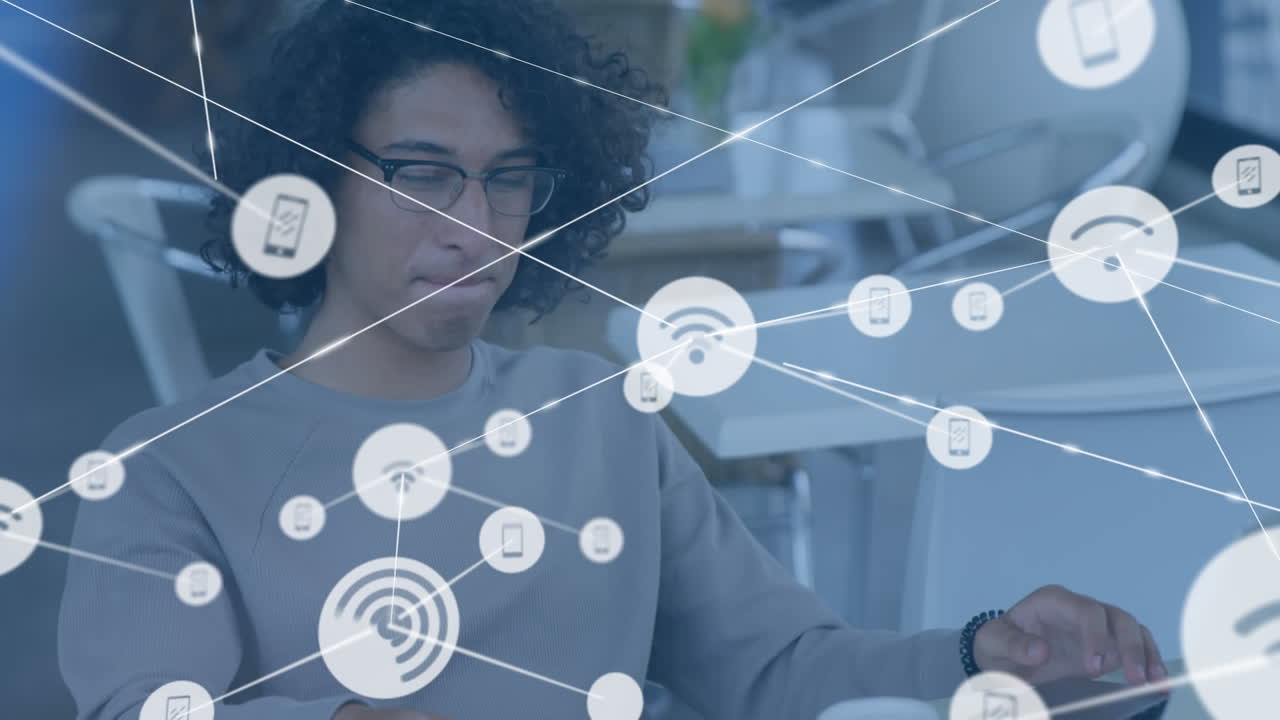 animación de iconos conectados sobre un hombre biracial hablando por teléfono y trabajando en una computadora portátil en cafés.