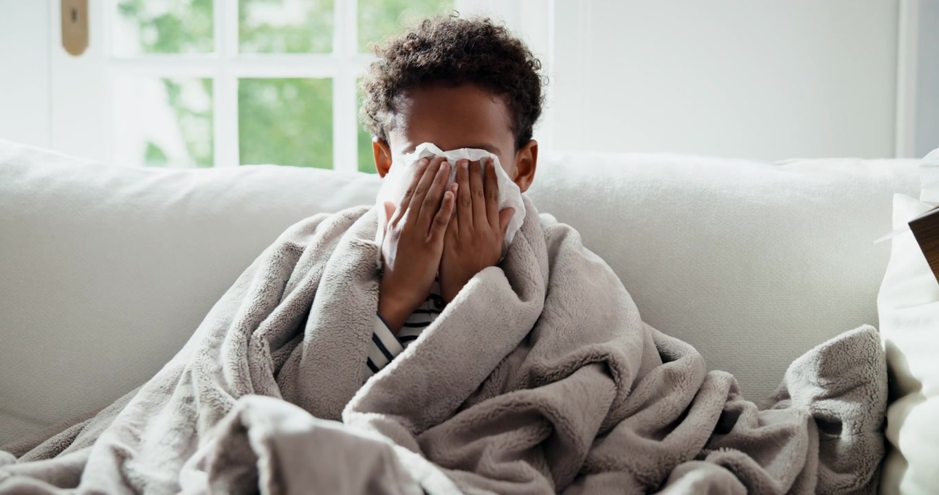 Young Boy Coughing and Blowing Nose While Wrapped in Blanket