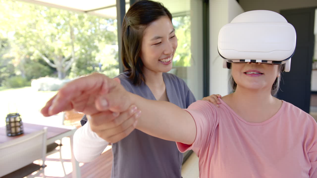 Using VR headset, senior asian woman receiving physical therapy at home with therapist