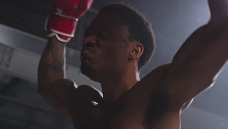 Primer-Plano-De-Un-Boxeador-Entrando-Al-Ring-Antes-Del-Inicio-Del-Combate-De-Boxeo-Saludando-Y-Saludando-A-Los-Fanáticos-Mientras-Chocan-Los-Guantes-Con-Una-Iluminación-Tenue